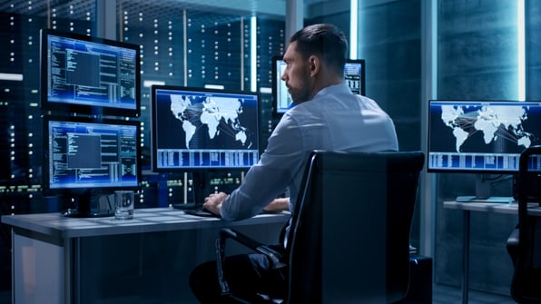 Young man sitting at computer in a cyber operations centre